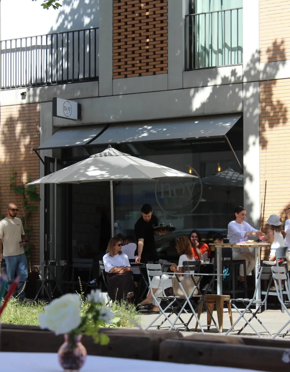 Guests sitting and chatting on the sunny terrace in front of noy