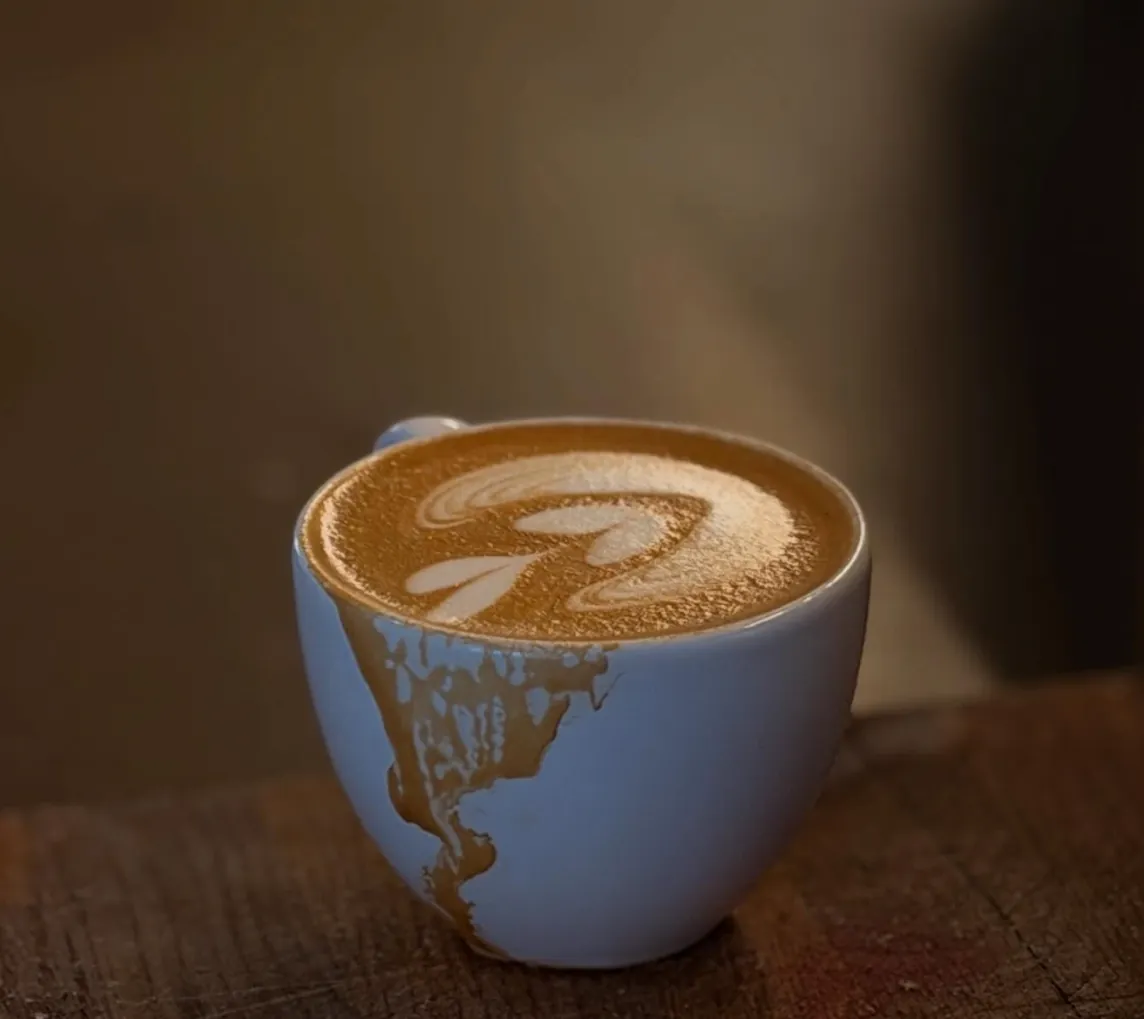 Cappuccino with latte art in a light blue cup on wood