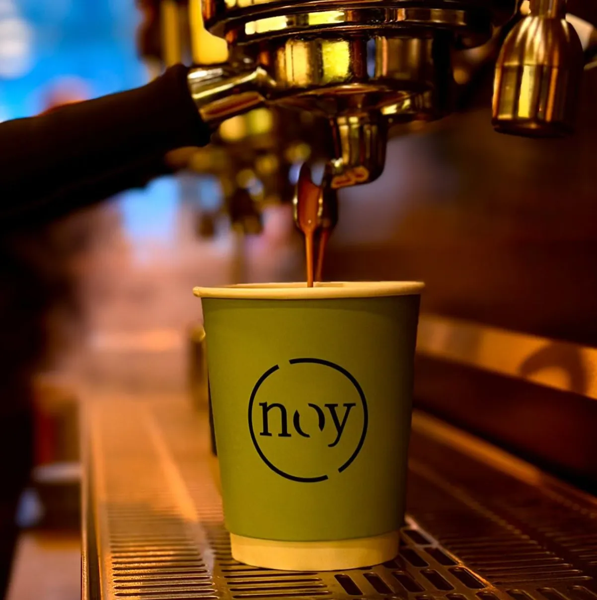 Espresso running from the machine into a green noy cup