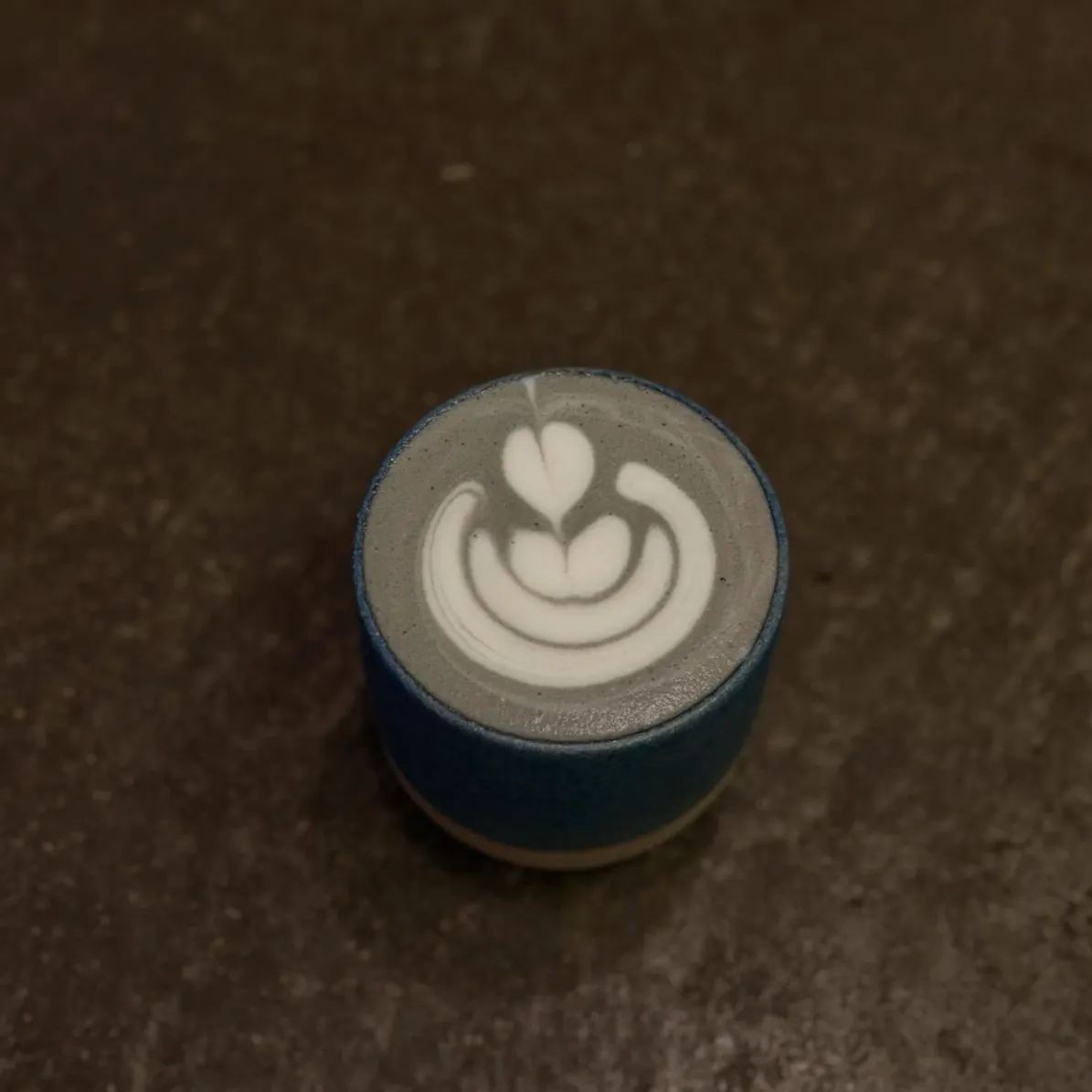 Blue cup with grey latte and latte art