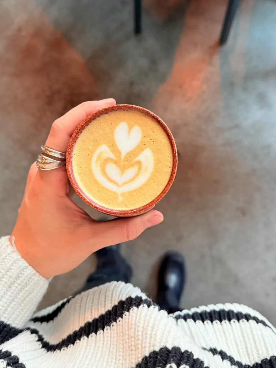 Latte with latte art from above, held in hand