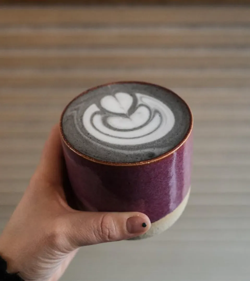 Purple ceramic cup with black latte and latte art